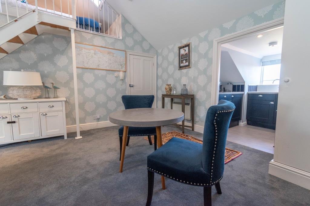 Lot: 29 - CHARACTERFUL FLAT IN A DESIRABLE NORFOLK COASTAL TOWN - Living room with Bedroom above and door to kitchen